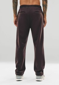 Dunkelbraune Sweatpants mit einem elastischen Bund, zwei Gesäßtaschen und einer entspannten Passform. Hergestellt aus weichem, strukturiertem Stoff.