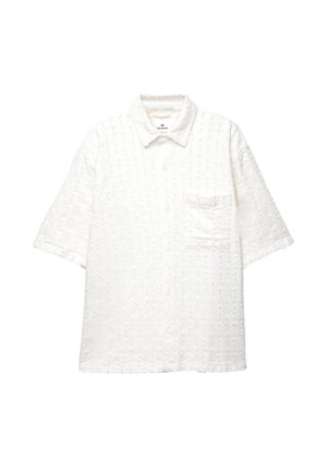 Chemise blanche à manches courtes avec un motif texturé, col polo, poche avant et fermeture à boutons. Fabriquée en tissu léger.