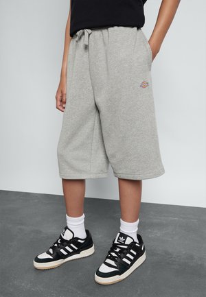 Grijze sweatshorts met zakken en een elastische tailleband, gecombineerd met zwart-witte sneakers en witte crew-sokken.