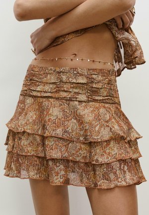 Jupe brune à plusieurs couches avec des ourlets ruffles et un motif paisley. Le matériau semble léger avec une finition texturée et un subtil éclat.