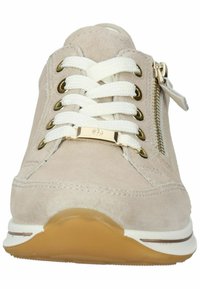 Beige Wildleder Sneaker mit weißen Schnürsenkeln, goldenen Akzenten und seitlichem Reißverschluss. Verfügt über eine abgerundete Gummisohle mit leichter Erhöhung.