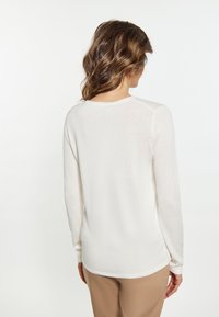 Langarmoberteil aus weichem Creme-Stoff, mit rundem Ausschnitt, gerippten Bündchen und lockerer Passform. Sichtbare Nähte verleihen dem Design Textur.