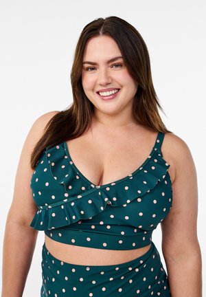Polka dot bikini set in dark green with pink dots. Features ruffled detailing along the top edge and a fitted band at the bottom.
