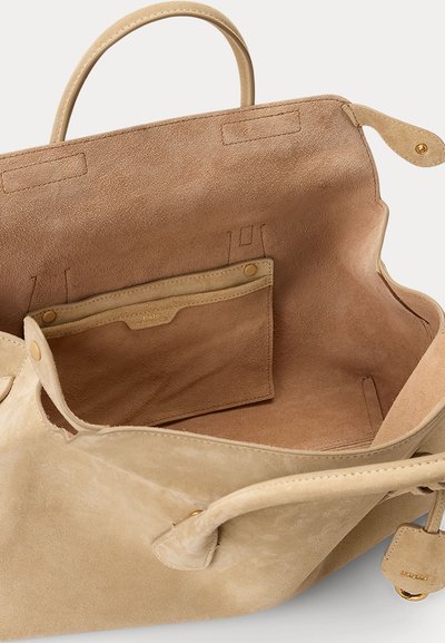 Μπεζ τσάντα ώμου από σουέτ με διπλές λαβές, ανοιχτό πάνω μέρος και εσωτερική θήκη με κλείσιμο με τρουκ και χρυσές λεπτομέρειες στα μεταλλικά εξαρτήματα.