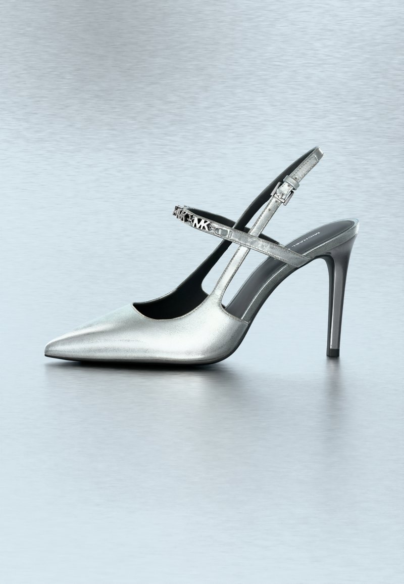 Chaussure à talon haut argentée avec un bout pointu et une bride ajustable ornée d'une boucle décorative. Texture métallique lisse avec un design élégant.