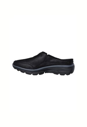 Black slip-on shoe with cushioned sole and textured tread, designed for comfort and easy wear.