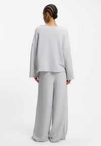 Graues Sweatshirt und Hose mit weitem Bein, aus weichem Stoff gefertigt. Verfügt über eine lockere Passform, ausgefranste Säume und tief angesetzte Schultern für Komfort.