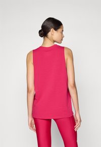 Débardeur sans manches en coton rose vif, avec un décolleté arrondi et une coupe décontractée. Texture lisse, avec des fentes sur les côtés pour plus de liberté de mouvement.