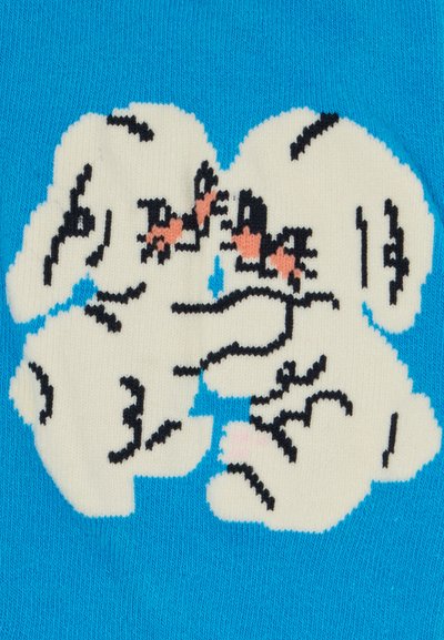 Adīta džemperis ar spilgti zilu fona, kurā attēlots balts un melns suns, papildināts ar rozā akcentiem un izteiksmīgām sejas izteiksmēm.