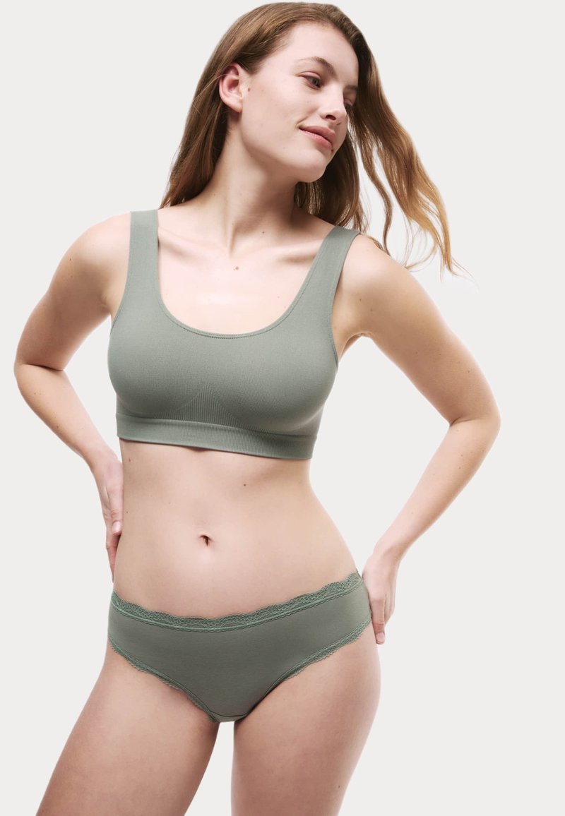 Ljusgrön ribbad bralette med breda axelband, parat med matchande shorts med scalloped spetsdetaljer. Slät textur, avslappnad passform.