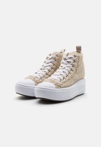 Högklackade sneakers med beige fluffigt överdel, vit gummitoa, vita skosnören och en tjock vit sula. Har en liten dragflik bak.
