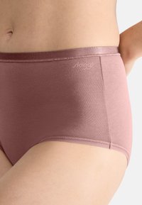 High-waisted, soft pink cotton underwear with a smooth texture and elastic waistband, featuring subtle branding on the side.