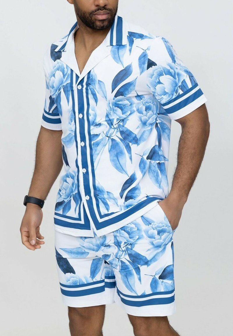 Chemise à manches courtes avec boutons et short assorti en blanc avec des motifs floraux bleus, présentant des accents rayés bleus et une coupe décontractée.