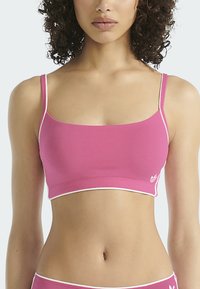 Růžový bralet s tenkými ramínky, s čtvercovým výstřihem a bílým zdobným lemováním. Vyrobeno z hladké, elastické látky.