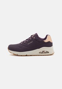 Chaussure de sport violette avec une tige en maille texturée, accents beige contrastants et amorti d'air visible dans la semelle. Présente un design à lacets.
