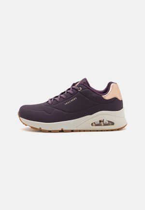 Purple athletic shoe with a textured mesh upper, contrasting beige accents, and visible air cushioning in the sole. Features lace-up design.