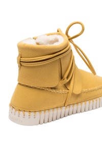 Bottine en daim tanné avec doublure en fourrure blanche, lacets à l'avant, détails cousus et semelle épaisse en caoutchouc blanc.