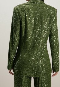 Groene sequin tuxedo jasje met een gestructureerde silhouet, met lange mouwen, textuur oppervlak en een notch kraag.