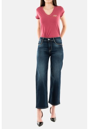 T-shirt bordeaux à col en V avec manches retroussées, associé à un jean en denim bleu foncé à jambes larges avec poches avant et finition soignée.