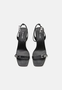 Sandales noires à talons avec un bout carré, des fines lanières, des accents en cuir texturé et un détail de boucle métallique. Semelle plate pour une stabilité optimale.