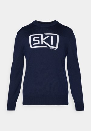 Pull en tricot navy à manches longues, col rond, avec un design logo "SKI" blanc sur le devant, texture lisse et poignets côtelés.
