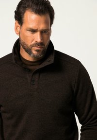 Donkerbruin pullover trui met een hoge kraag, drie knopenlijst en textuurstof. Bevat een subtiel gemêleerd patroon.