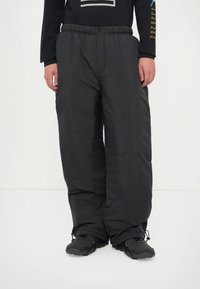 Pantaloni isolati neri con un'ampia vestibilità e una vita elasticizzata. Presentano una texture liscia e aree delle caviglie rinforzate.