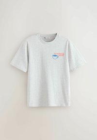 Lysegrå T-shirt med korte ærmer og rund hals, med en blå kaffekop og lyserød tekst "The Morning Boost" på venstre bryst.