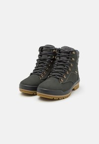 Wandelboots in donkergrijs synthetisch materiaal met een gestructureerde grijze stofkraag. Voorzien van metalen oogjes, bruine accenten en een robuuste rubberen zool.