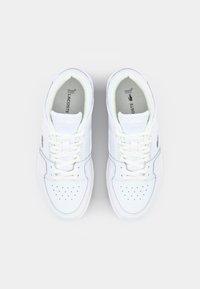 Białe skórzane sneakersy z perforowanym czubkiem, płaskimi białymi sznurowadłami i zielonym logo krokodyla z boku, posiadające wyściełaną wkładkę.