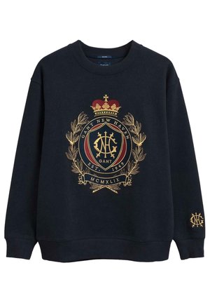 Granatowa bluza z nadrukowanym złotym herbem, na którym znajduje się korona, wieniec laurowy i tekst "GANT NEW HAVEN EST. 1949".