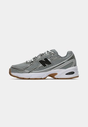 Grijze mesh hardloopschoen met zwarte accenten en witte veters. Heeft een gevoerde witte zool en gestructureerde gumrubberen buitenzool.