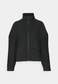 Giacca nera a spina di pesce con colletto alto, chiusura con zip e due tasche frontali. Presenta un design strutturato e un tessuto testurizzato.