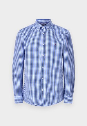 Chemise en vichy bleu et blanc avec un col boutonné, des manches longues et un petit logo sur la poitrine. Fabriquée en tissu en coton.