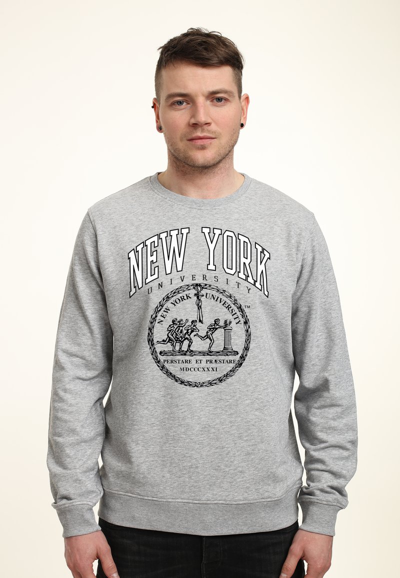 Grå sweatshirt med långa ärmar, med "NEW YORK UNIVERSITY" i svart text och en centralt placerad logotyp med ett emblematiskt sigill.