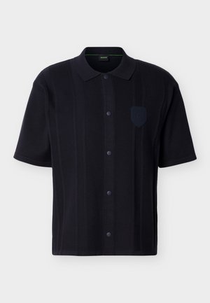 Μαύρο πουκάμισο με κοντά μανίκια, κατακόρυφες υφασμένες ρίγες, γιακά και μικρό σήμα στο αριστερό μέρος του στήθους.