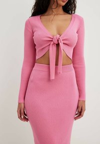 Rosa ribbatdt tvådelad outfit som består av en kortärmad topp med knytning framtill och en matchande penkjol för en figurnära silhuett.