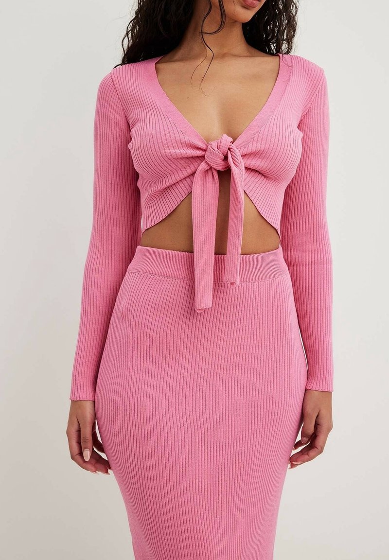 Rosa ribbatdt tvådelad outfit som består av en kortärmad topp med knytning framtill och en matchande penkjol för en figurnära silhuett.