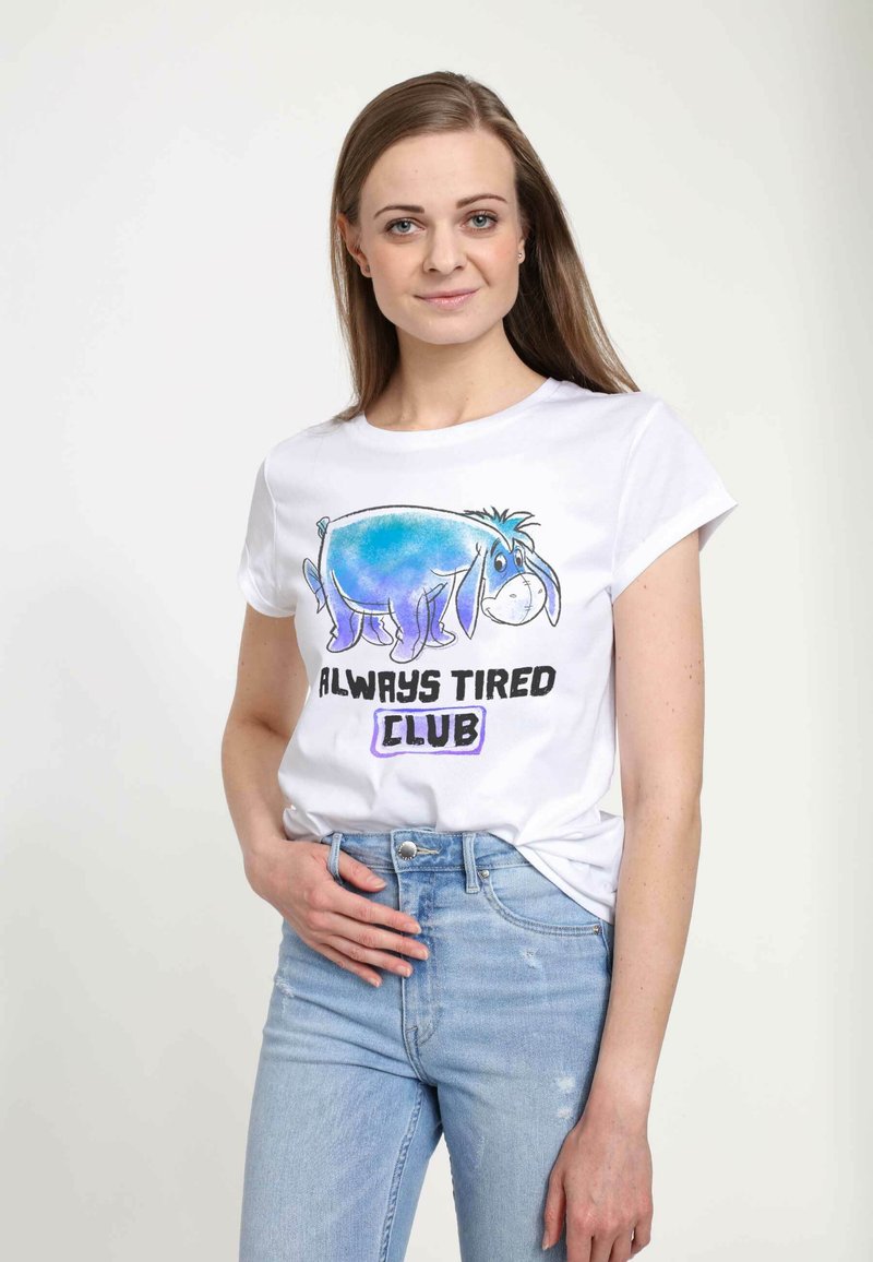 Bílý bavlněný tričko s modrou grafikou Eeyora a textem "ALWAYS TIRED CLUB" v tučném černém písmu. Krátké rukávy, volný střih.