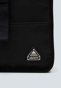 Borsa in morbido tessuto nero con una patch a forma triangolare. Presenta una texture liscia, un design elegante e un accento argentato prominente con "JACK1T."