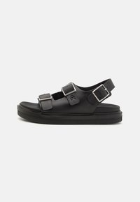 Svarta sandaler med platt sula, utrustade med två justerbara spännen och ett bakre rem. Tillverkade av slätt syntetmaterial med en ren design.