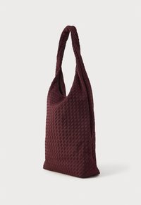 Kootud ostukott tumepunases burgundia toonis, millel on üks keeratud käepide ja pehme tekstuur, ning ruumikas, struktureerimata disain.