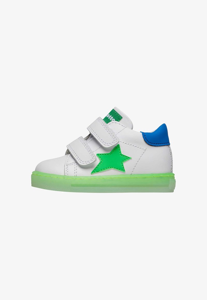 Baskets blanches avec accent étoile verte, talon bleu et doubles sangles velcro. La semelle verte transparente offre un contraste vibrant.
