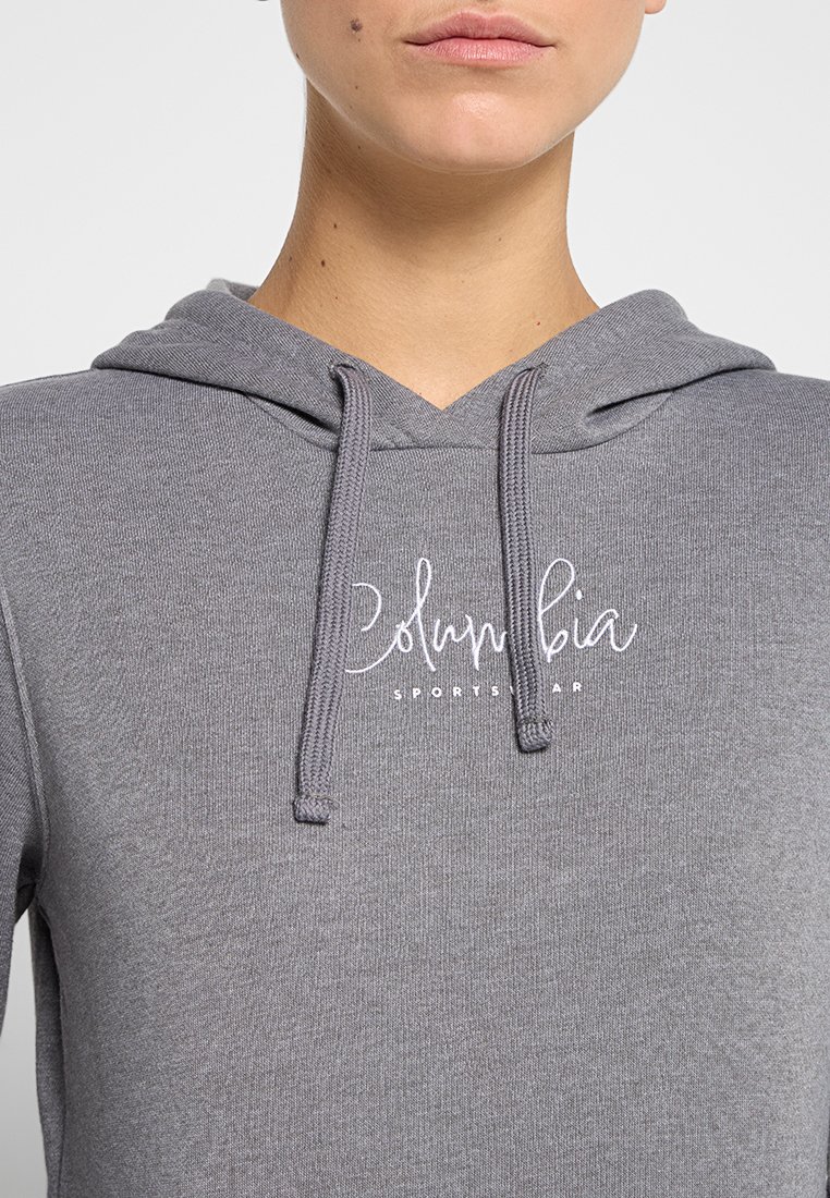 Sudadera con capucha gris, con un bolsillo frontal, cordones y el logo blanco de "Columbia Sportswear". Textura de tela suave, diseño casual.