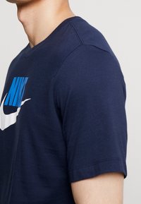 Marinblå bomullströja med korta ärmar, med en framträdande blå och vit Nike-logotyp över bröstet. Slät textur, normal passform.