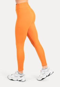 Oranje leggings met een hoge tailleband, ontworpen voor flexibiliteit. Gemaakt van gladde stof, met een slanke, nauwsluitende pasvorm.