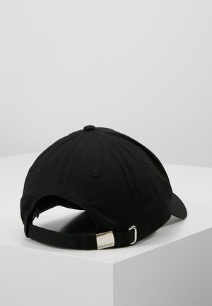Sort Calvin Klein baseballcap med justerbar rem og metalspænde, set bagfra på en hvid overflade.