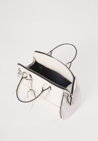 Sac à main en cuir blanc avec des bordures noires, doté de poignées doubles, d'une fermeture éclair en haut et d'un intérieur spacieux avec une doublure noire.