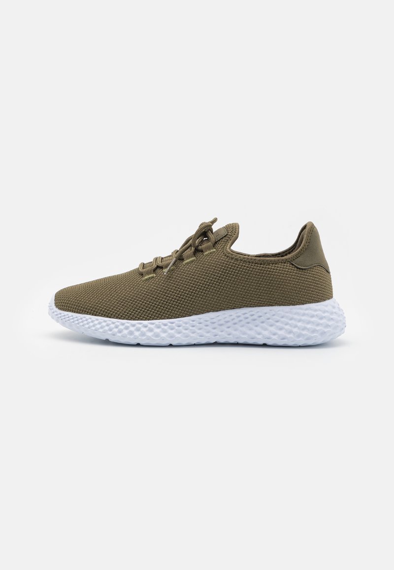 Baskets vert olive avec une tige en mesh texturé, semelle épaisse blanche et design à lacets. Présente une silhouette épurée.