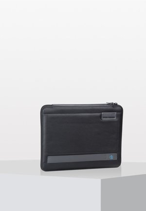 Custodia per laptop in pelle nera con una texture liscia, caratterizzata da una striscia di accento grigia e una stampa dell'icona di alimentazione sul davanti. Chiusura con cerniera.